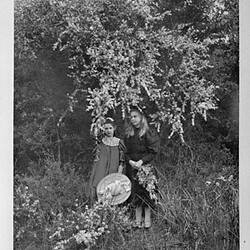 Two girls standing under a flowering tree.