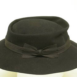 Black hat with black hat band tied into bow.