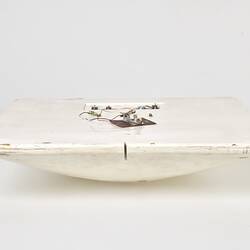 Scuffed white plastic square plate with curved base and rounded corners. Profile.