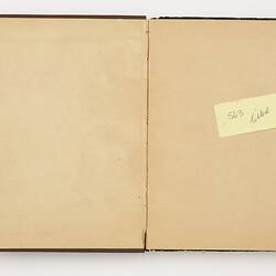Open book with off white ruled pages. Yellow 'Post it' note on right page.