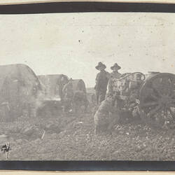 Row of cylindrical corrugated iron huts on left and soldiers and cart on right.