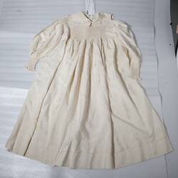 Child's cream silk dress on packaging materials.