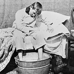 Negative - Frank Stephenson Seated on Bed With Feet in a Washtub, Merrigum, Victoria, 1910