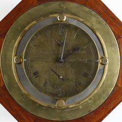 Detail of brass clock face. Wooden background.