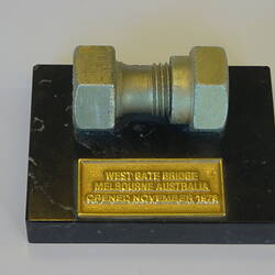 Bolt mounted on marble base with metal plaque.