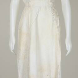 White apron with red cross on front worn by mannequin, front view.