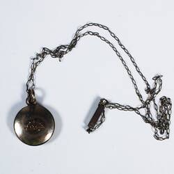 Round silver locket on chain with oval links, rising sun motif on front surfaces of locket.