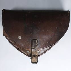 Brown leather case, triangular in shape, with a flap front, secured by a small metal buckle at base.