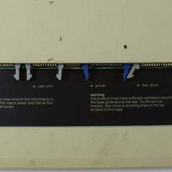 Underside of discoloured, stained beige computer console with printed text.