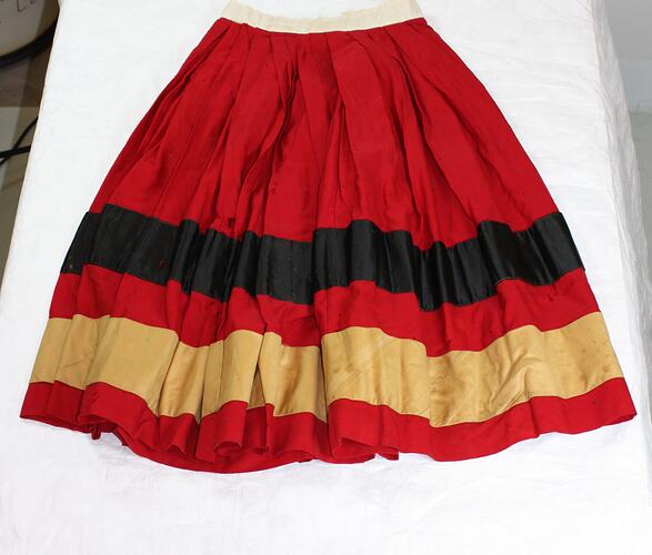 Red gathered skirt, wide silk black and cream (discoloured) stripe. Narrow white waistband.