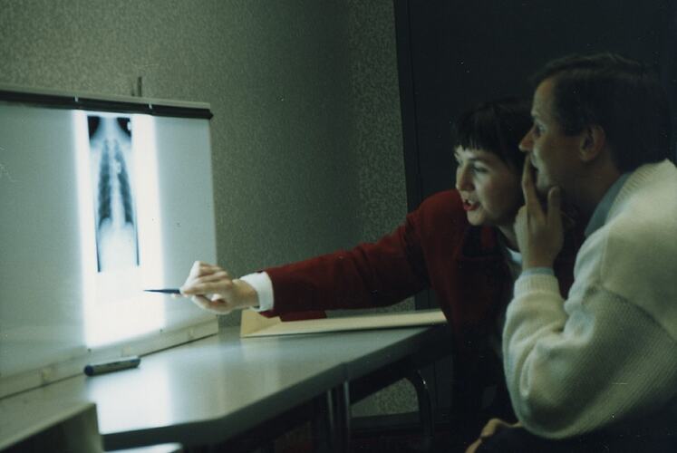 Woman pointing to x-ray, man looking on.