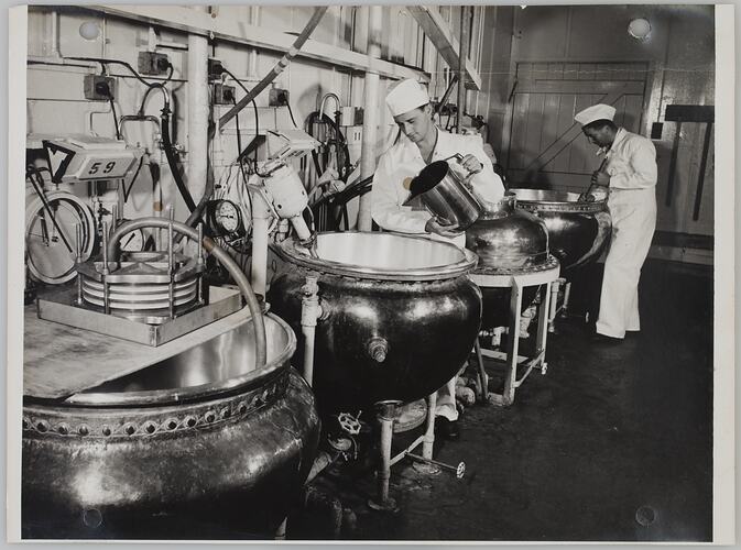 Two men with four large round vats.