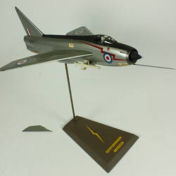 Silver model aeroplane. Blue, white and red rondels on wings and fuselage. On stand.