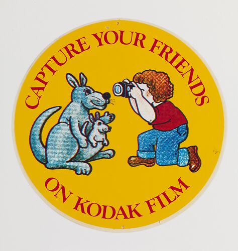 Cartoon of a child photographing a kangaroo with joey, on a round sticker.