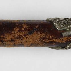 Detail of leather riding crop handle with silver cap and emblem.