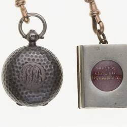 Detail of silver watch chain with silver sovereign case and miniature book.