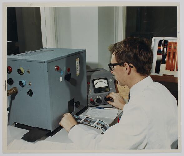 Man seated at a desk with a machine.