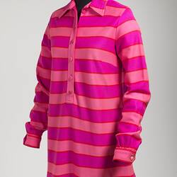 Angle view of pink striped mini polo-shirt dress. Long sleeve with collar, cuffs, front buttons.