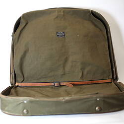 Inside of khaki canvas valise showing strap and zip.