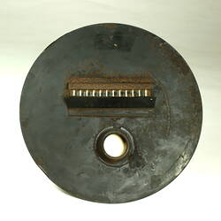 Circular metal plate painted black with rectangular opening.