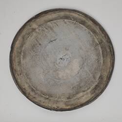 Round scuffed metal lid with lip.