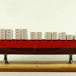 Container ship with red hull facing right.