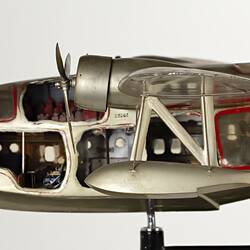 Green-silver model aeroplane on stand. Cutaways on side show interior. Close-up of front left section.