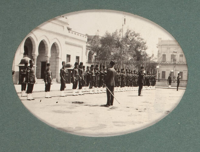 Row of soldiers on parade in front of building.