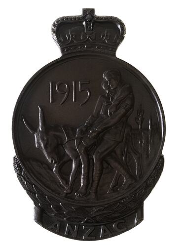 Roundish brown medal with crown atop and wreath below. Features Simpson and his donkey.