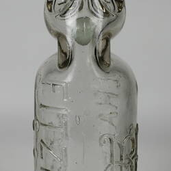 Clear glass bottle with raised inscription.