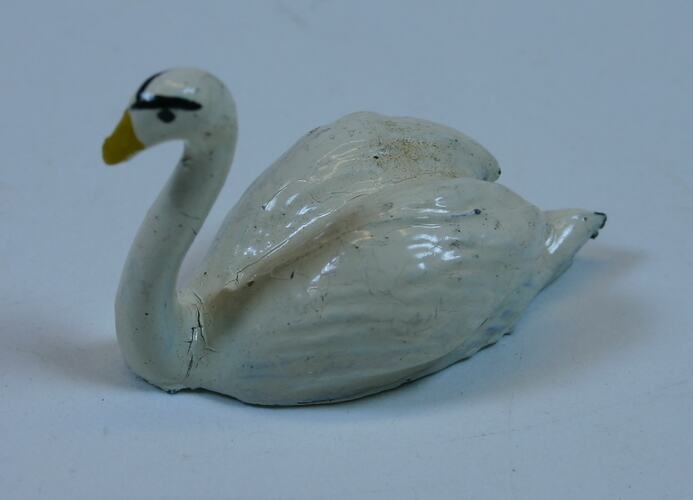 Toy metal white swan. Black eyes and yellow beak.