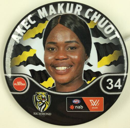 Metal round badge with black, white and yellow. Has woman's smiling face in colour, tiger and number 34.