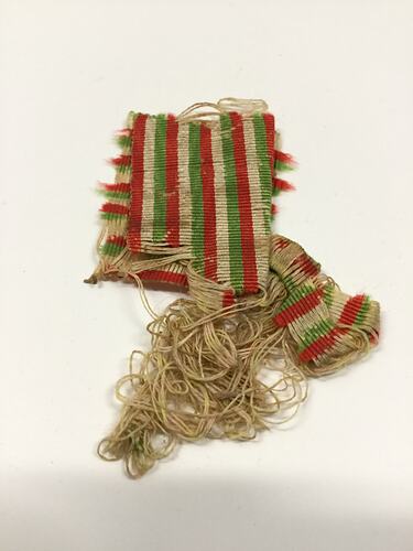 Worn and frayed green, red and white striped medal ribbon.
