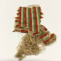 Worn and frayed green, red and white striped medal ribbon.