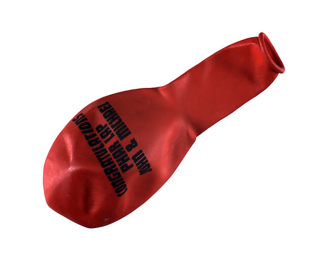 Uninflated red rubber balloon with black text.