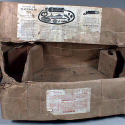 Damaged cardboard box with applied labels, half open.