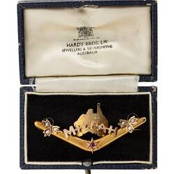 Back of gold boomerang with a map of Australia behind the words 'Mizpah'. Has seed pearls and a small ruby. In box.