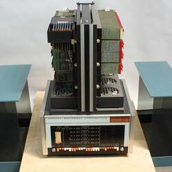 Black, grey computer. Horizontally stacked circuit boards above switches. Removed blue/tinted case at sides.