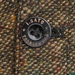 Dark button on brown trousers with maker's name and address. I. SATO TOORAK ROAD.