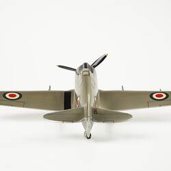 Back view of model aeroplane, silver with a black propeller and wheels.