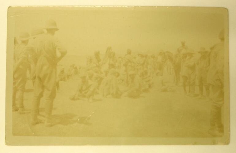 Seated men watched over by standing soldiers.