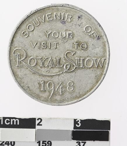 Round silver coloured medal with text.