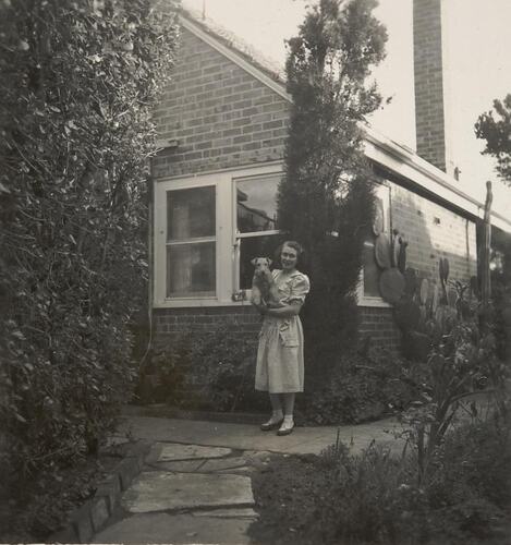 Digital Photograph - Woman Standing in Front Garden Holding Dog, Black Rock, 1948