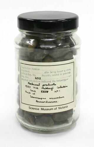 Glass jar containing nuts, with a paper label.