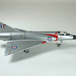 Right side of plastic silver model aeroplane. Red stripes and red, white and blue bulleyes on wings.