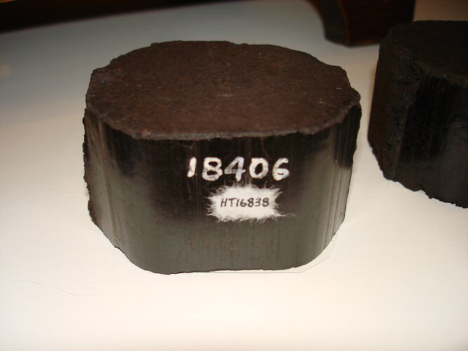 Dark brown rounded coal briquette. White numbers on side.