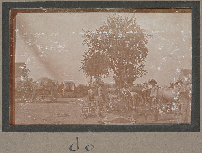 Men with shovels in right foreground with horses behind, four wagons in the left, tree in background.