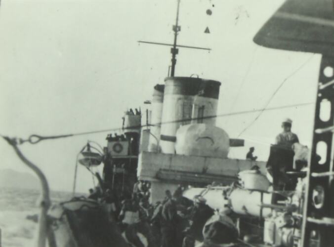 Soldiers on the deck of a military battleship, ocean in the background.