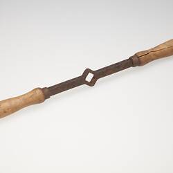 Italian pasta maker, iron rod with diamond hole in centre and a wooden handle on each end.