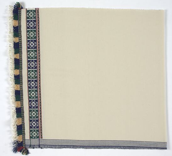 Corner of white fabric, green and blue border.